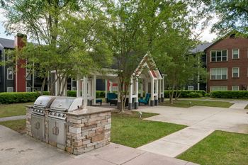 a large grill sits in the middle of a grassy area with a building in the background at Elme Druid Hills, Atlanta, 30329